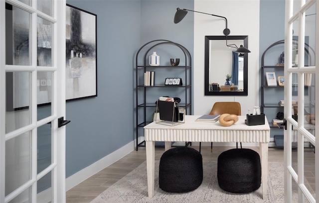 office with french doors and light hardwood / wood-style flooring