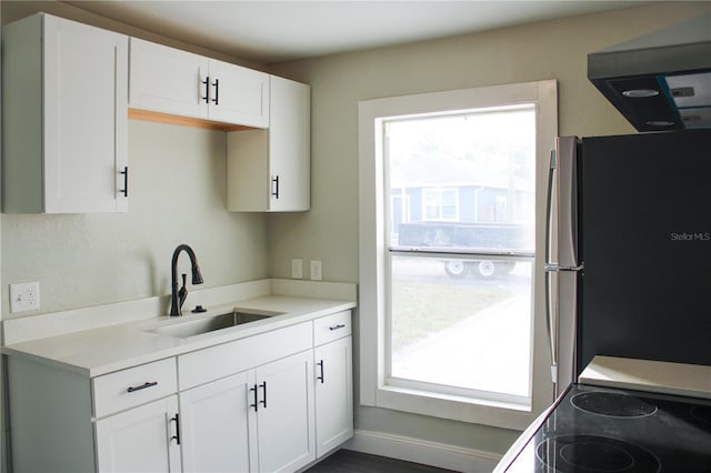 kitchen featuring a healthy amount of sunlight, white cabinetry, sink, and stainless steel refrigerator