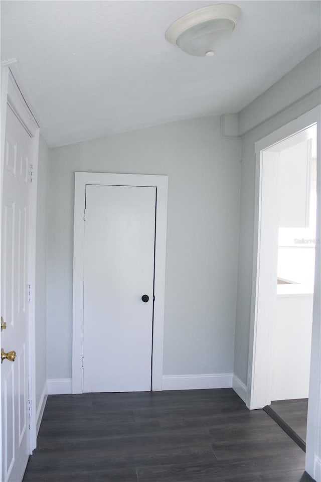 unfurnished bedroom with dark hardwood / wood-style flooring, a closet, and vaulted ceiling