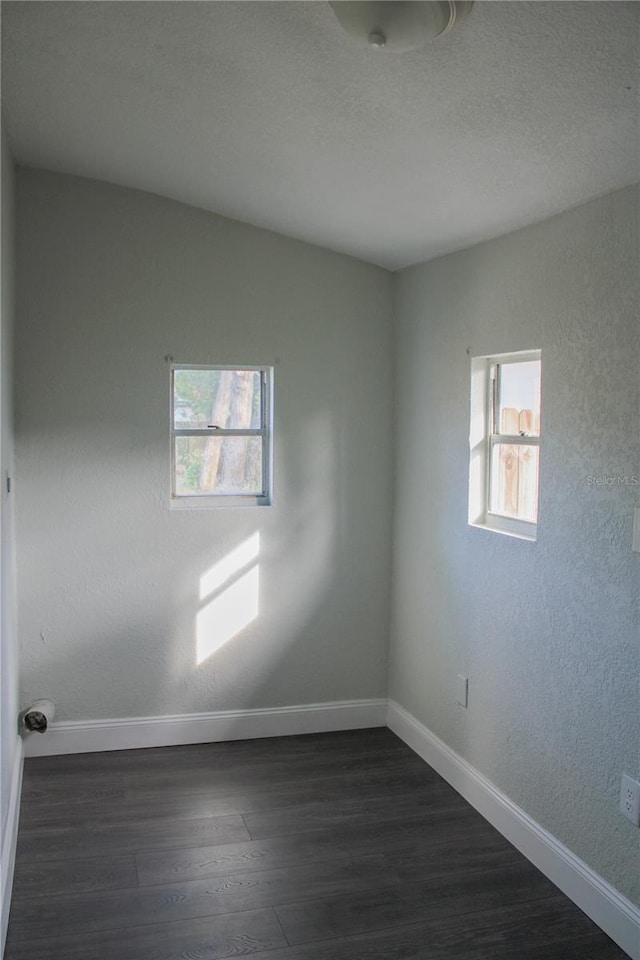 unfurnished room with dark hardwood / wood-style floors and a healthy amount of sunlight