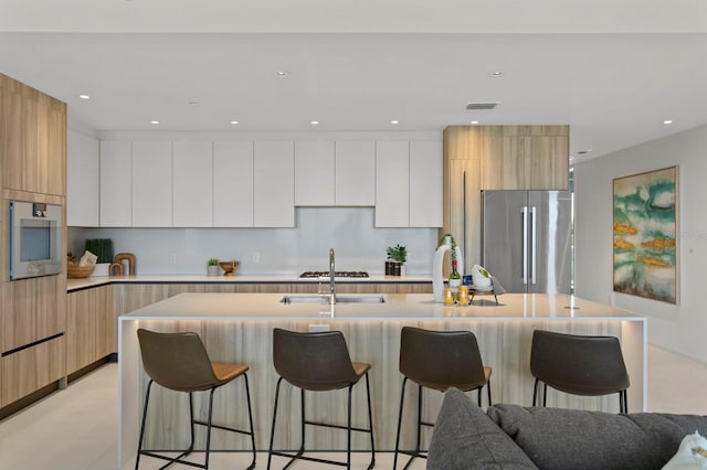 kitchen with white cabinetry, stainless steel appliances, and an island with sink