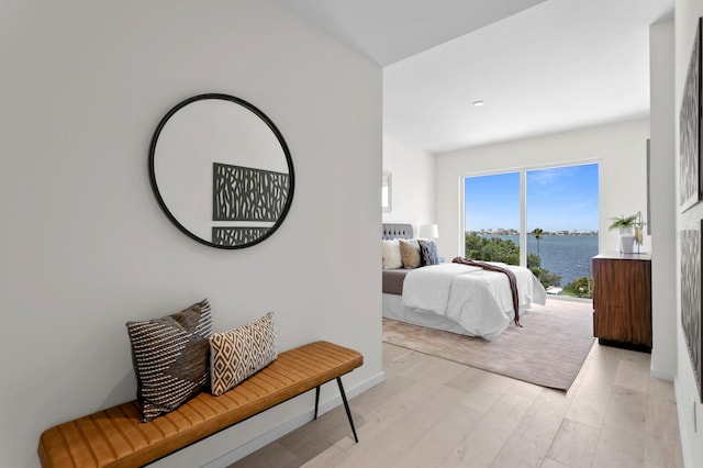 bedroom featuring light hardwood / wood-style flooring and a water view