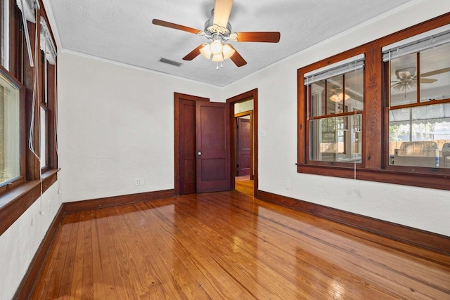 spare room with ornamental molding, light hardwood / wood-style floors, a textured ceiling, and ceiling fan