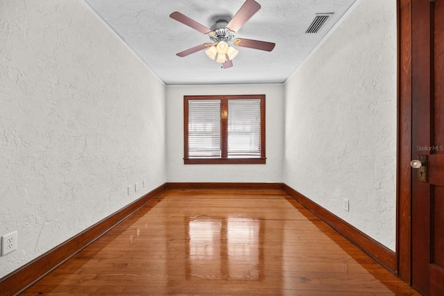 empty room featuring light wood-type flooring, a textured ceiling, crown molding, and ceiling fan