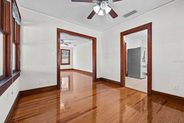 unfurnished room with a textured ceiling, hardwood / wood-style floors, ceiling fan, and crown molding