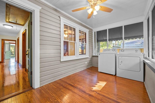 clothes washing area featuring washer and dryer, wooden walls, light hardwood / wood-style flooring, and ornamental molding