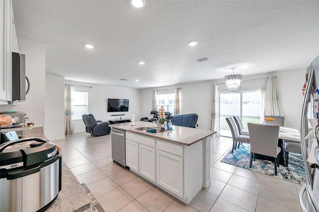 kitchen with stainless steel appliances, a kitchen island with sink, sink, light tile patterned floors, and white cabinetry