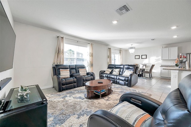 living room featuring light tile patterned floors, a textured ceiling, and a chandelier