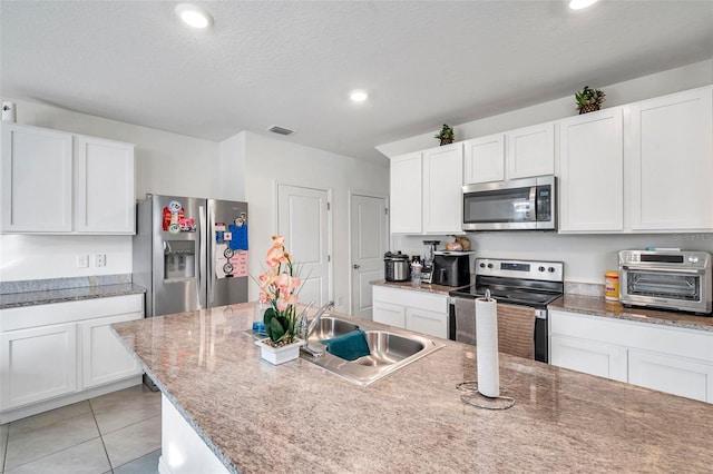 kitchen with white cabinets, sink, stainless steel appliances, and a textured ceiling