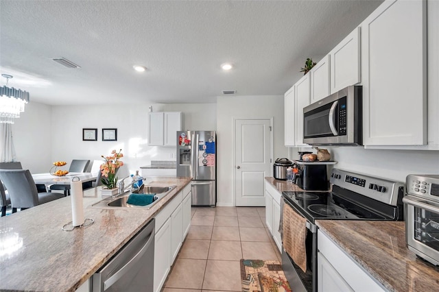 kitchen with sink, light tile patterned floors, a textured ceiling, appliances with stainless steel finishes, and white cabinetry