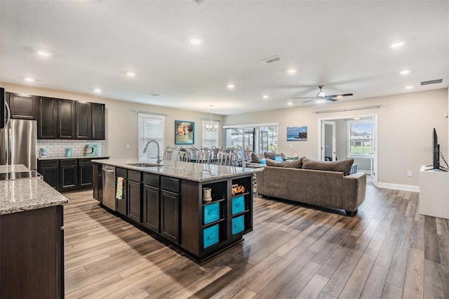 kitchen featuring sink, light hardwood / wood-style flooring, an island with sink, appliances with stainless steel finishes, and dark brown cabinetry