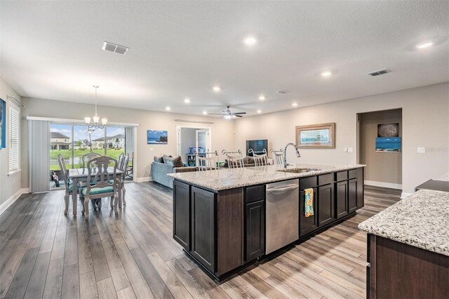 kitchen featuring dishwasher, pendant lighting, light wood-type flooring, and a kitchen island with sink