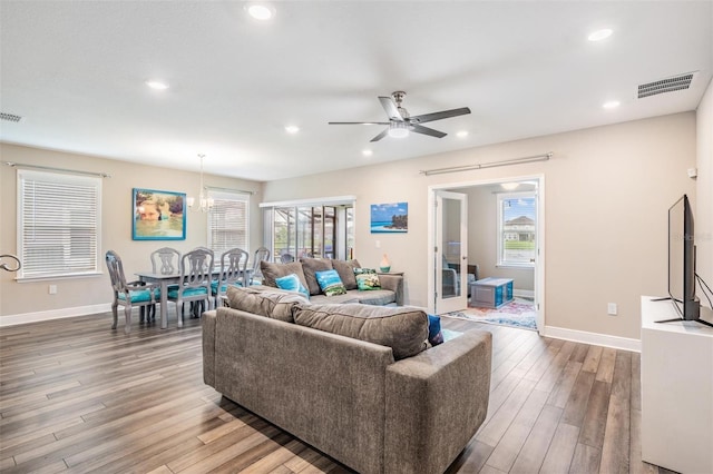 living room featuring plenty of natural light, light wood-type flooring, and ceiling fan with notable chandelier