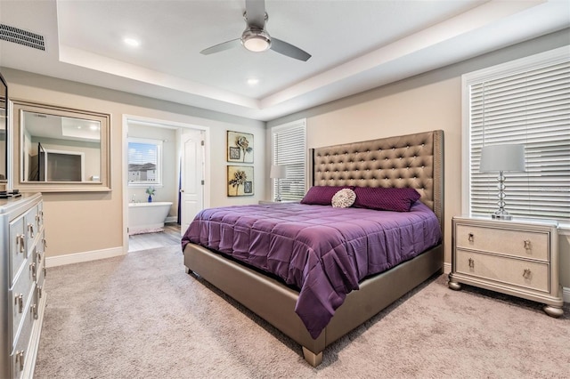 carpeted bedroom featuring ceiling fan, a raised ceiling, and ensuite bathroom