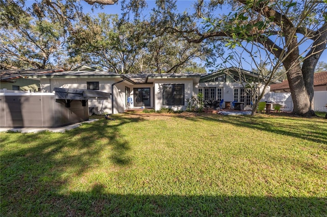 back of property featuring a lawn and a jacuzzi