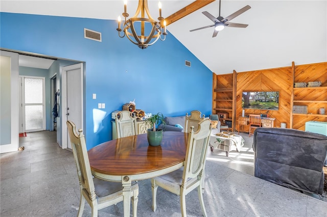 dining room featuring beam ceiling, ceiling fan with notable chandelier, high vaulted ceiling, and wooden walls