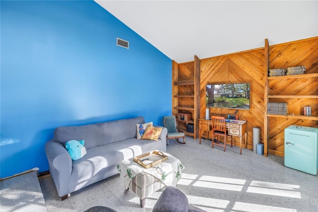 living room featuring high vaulted ceiling and wood walls