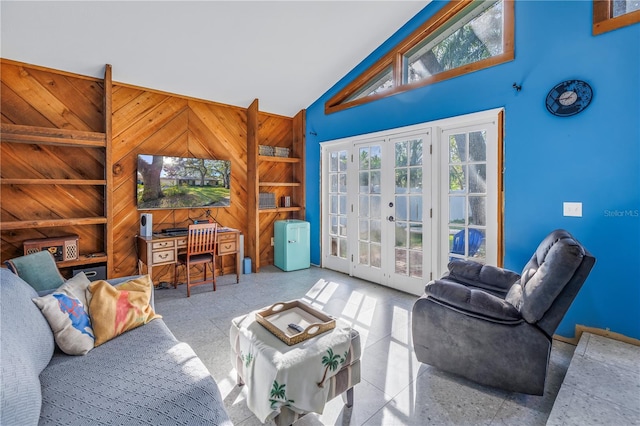 living room featuring french doors, high vaulted ceiling, and wood walls