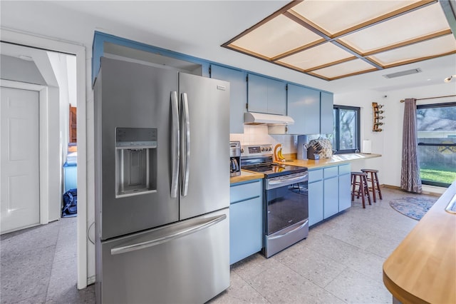 kitchen with blue cabinetry, appliances with stainless steel finishes, butcher block countertops, and a healthy amount of sunlight