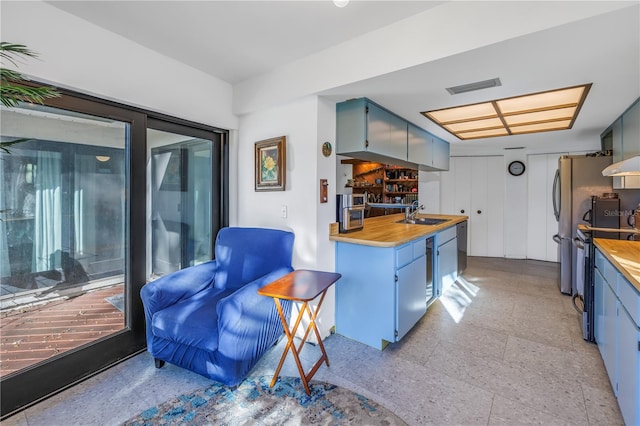 kitchen with blue cabinetry, island exhaust hood, and wooden counters