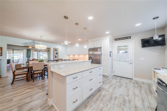 kitchen featuring a center island, stainless steel appliances, light hardwood / wood-style flooring, decorative light fixtures, and white cabinets