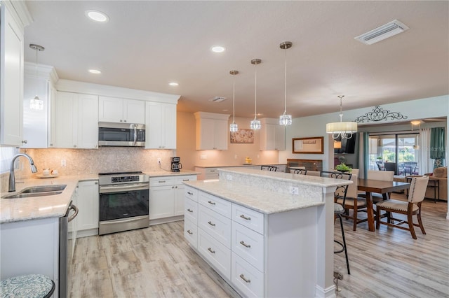 kitchen with white cabinets, a kitchen island, sink, and stainless steel appliances