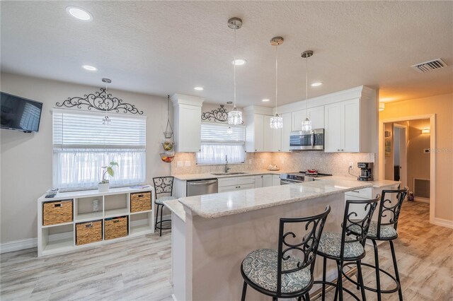 kitchen with white cabinets, decorative light fixtures, and appliances with stainless steel finishes