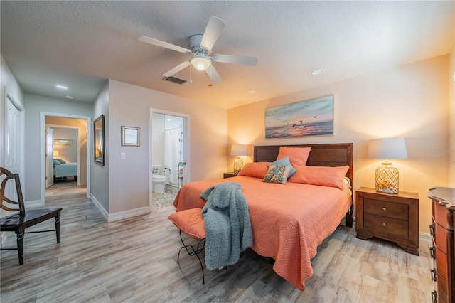 bedroom with ensuite bathroom, ceiling fan, a textured ceiling, and light wood-type flooring