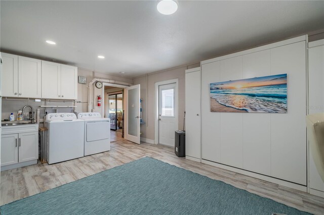 laundry room with cabinets, separate washer and dryer, sink, and light hardwood / wood-style flooring