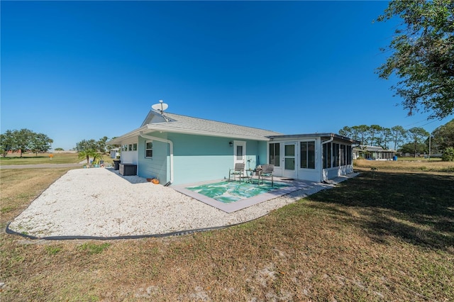 rear view of property with a lawn, a patio area, and a sunroom