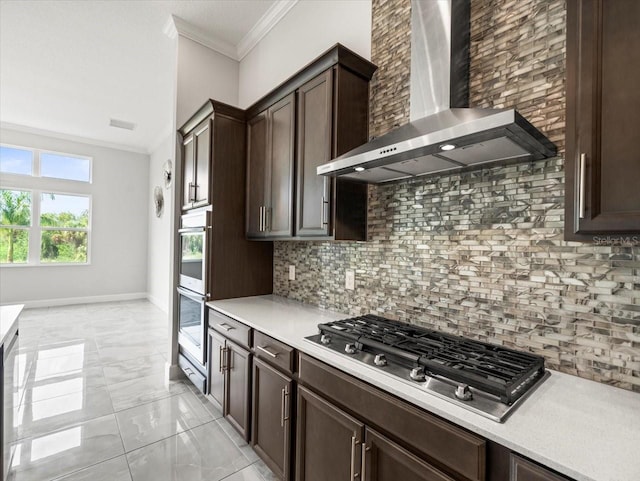 kitchen with dark brown cabinetry, wall chimney exhaust hood, tasteful backsplash, appliances with stainless steel finishes, and ornamental molding