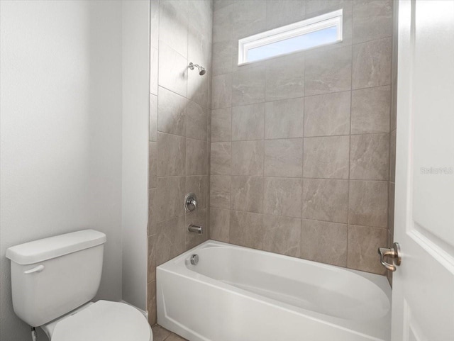 bathroom featuring tiled shower / bath combo and toilet