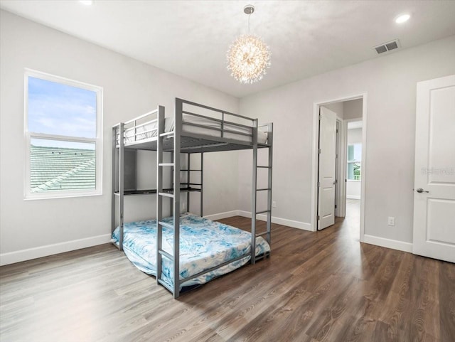 bedroom featuring hardwood / wood-style floors, multiple windows, and an inviting chandelier