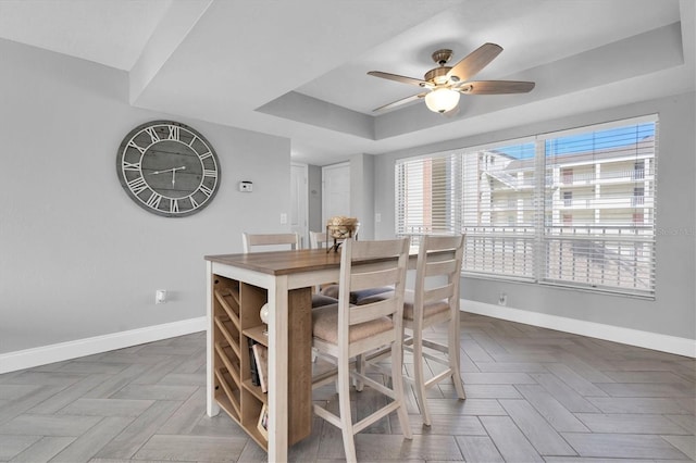 dining space featuring a raised ceiling, ceiling fan, and parquet floors