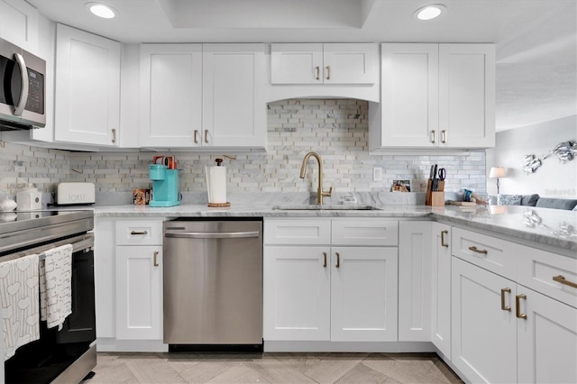 kitchen featuring appliances with stainless steel finishes, light stone counters, white cabinetry, and sink