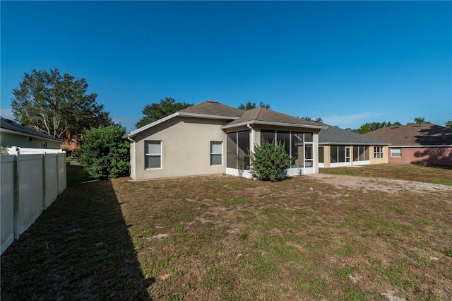 rear view of property featuring a sunroom and a yard