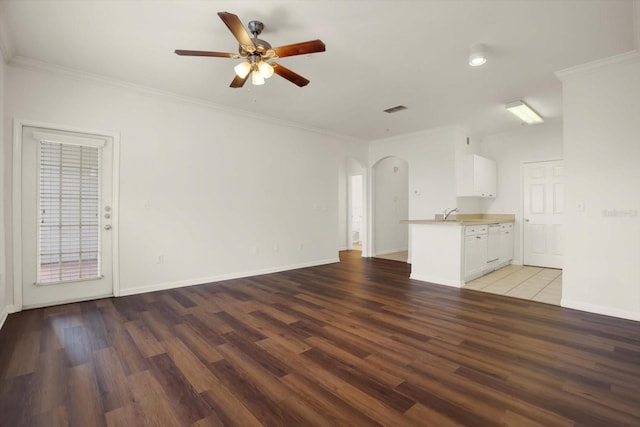 unfurnished living room with ceiling fan, dark wood-type flooring, and ornamental molding