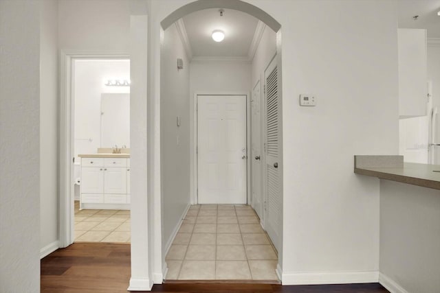 hall featuring ornamental molding, sink, and light tile patterned floors