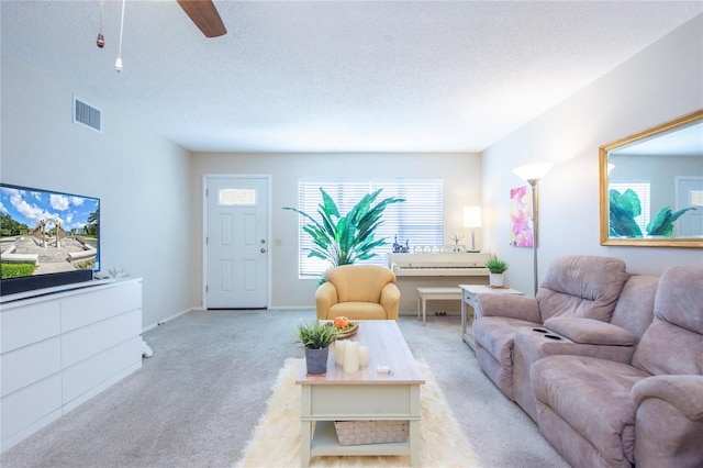 living room with ceiling fan, light colored carpet, and a textured ceiling