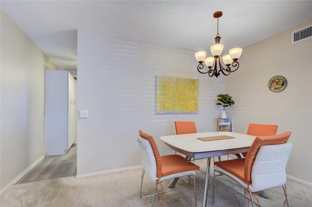 carpeted dining area with a textured ceiling and an inviting chandelier