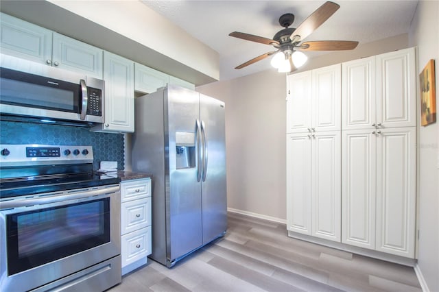 kitchen featuring light hardwood / wood-style floors, tasteful backsplash, ceiling fan, white cabinetry, and appliances with stainless steel finishes