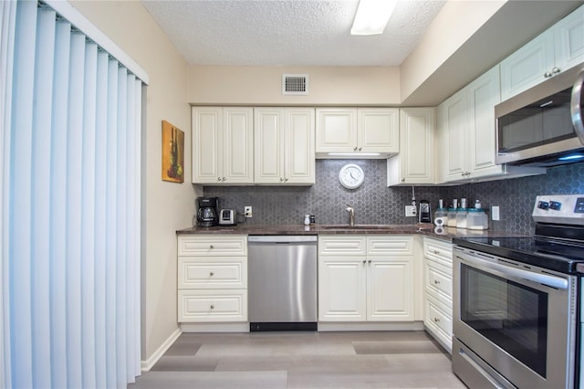 kitchen with white cabinetry, sink, appliances with stainless steel finishes, tasteful backsplash, and a textured ceiling