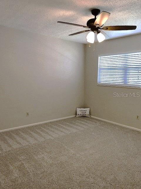 unfurnished room with ceiling fan, a textured ceiling, and carpet floors