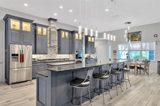 kitchen with a large island, decorative light fixtures, stainless steel appliances, and dark stone countertops