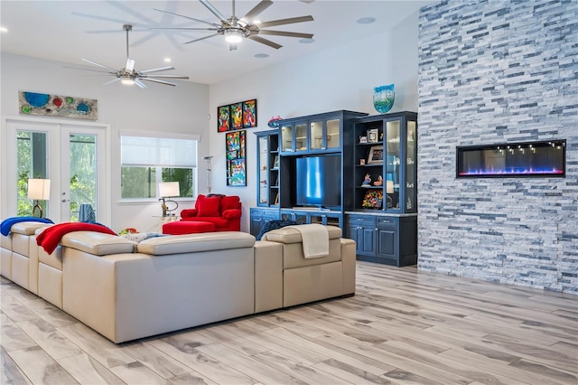 living room with a high ceiling, ceiling fan, and light hardwood / wood-style flooring