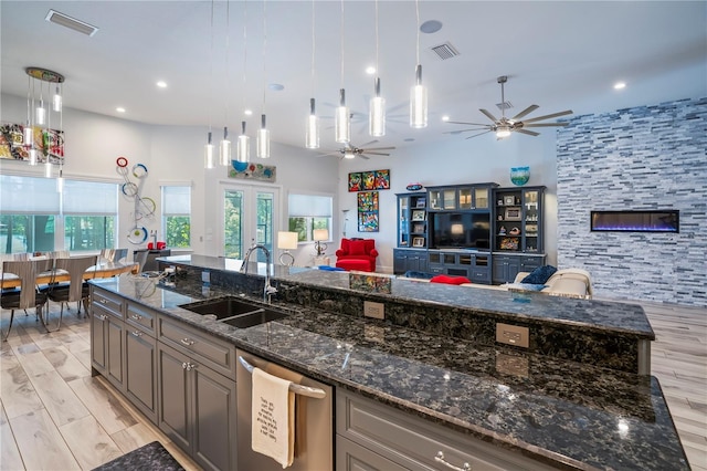 kitchen featuring decorative light fixtures, dishwasher, sink, and dark stone countertops