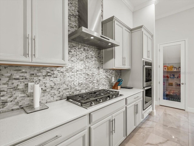 kitchen featuring wall chimney exhaust hood, crown molding, appliances with stainless steel finishes, and tasteful backsplash