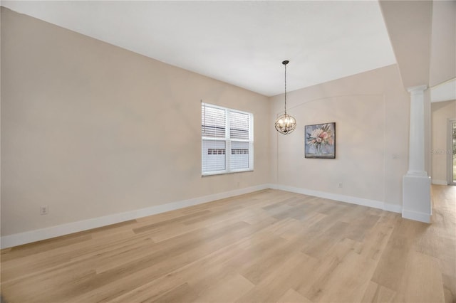 interior space featuring light wood-type flooring, a chandelier, and decorative columns