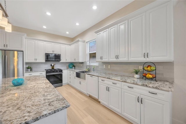 kitchen featuring stainless steel appliances, light wood-type flooring, decorative backsplash, sink, and white cabinets