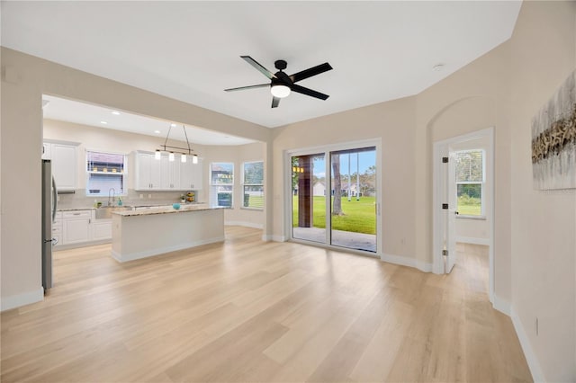 unfurnished living room with ceiling fan, sink, and light hardwood / wood-style flooring